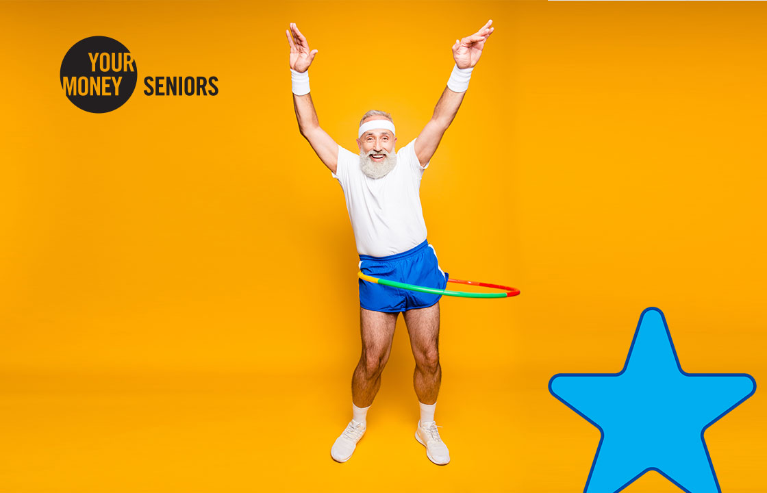 senior man in workout clothes with a hula hoop around his waist and hands up in the air